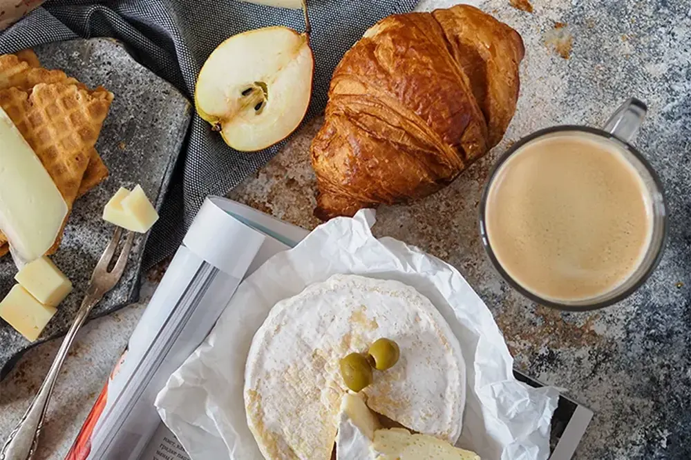 Frukostbord med croissant, camembert och kaffe